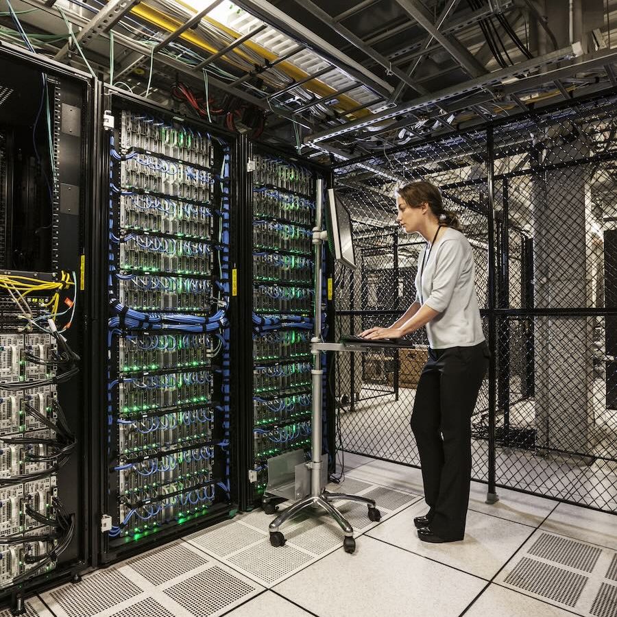 Caucasian woman technician working on computer servers in a server farm.